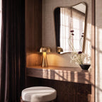 Clérachic gold table lamp glows warm on a vanity console, its dome shade catching afternoon light.