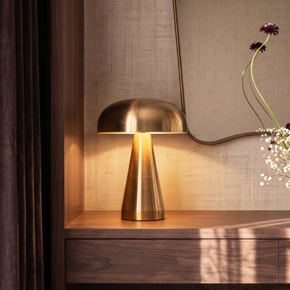 Clérachic gold table lamp detail: the brushed dome shade and tapered cone base beside a curved mirror.
