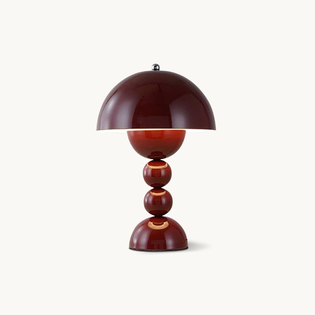 A wine red Clérachic table lamp with a dome shade over a base of stacked spheres, on a plain off-white backdrop.