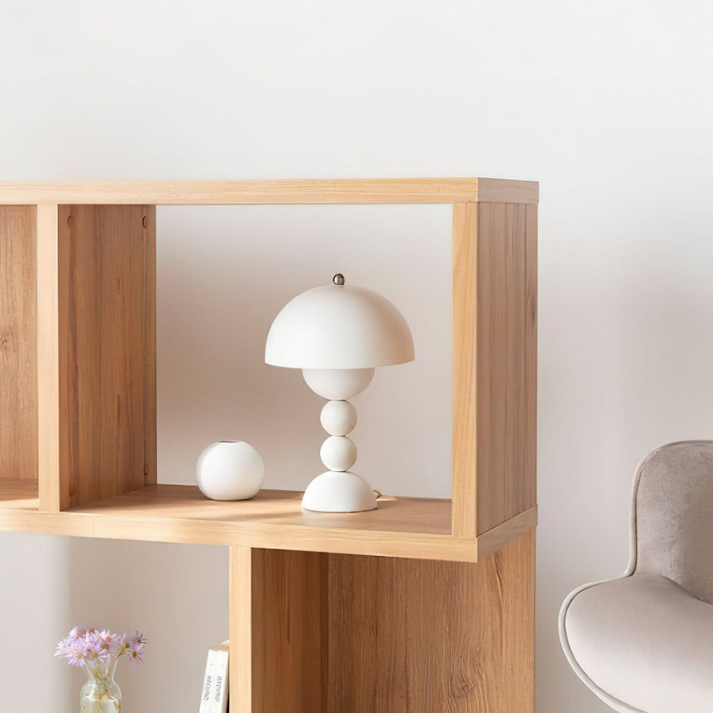 White Clérachic dome lamp sitting in a light wood open shelf, with a round white vase next to it and a chair behind.