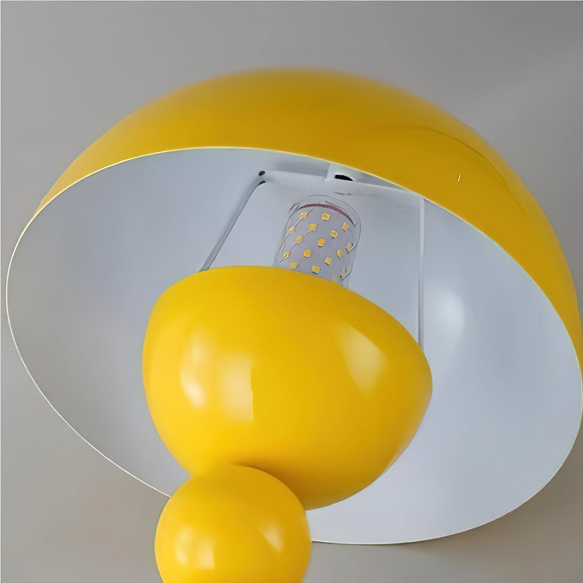 Looking up under the yellow dome of this Clérachic lamp, with the bulb and white inner lining visible above the base.
