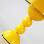Close view of the glossy yellow stacked spheres and the base dome on this Clérachic table lamp.