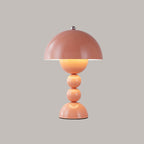 A pink Clérachic dome lamp with a warm glowing centre and a charging port on its base, on a grey backdrop.