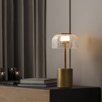 A finger touches the metal cap of this Clérachic crackle glass table lamp, which glows warm inside the dome.