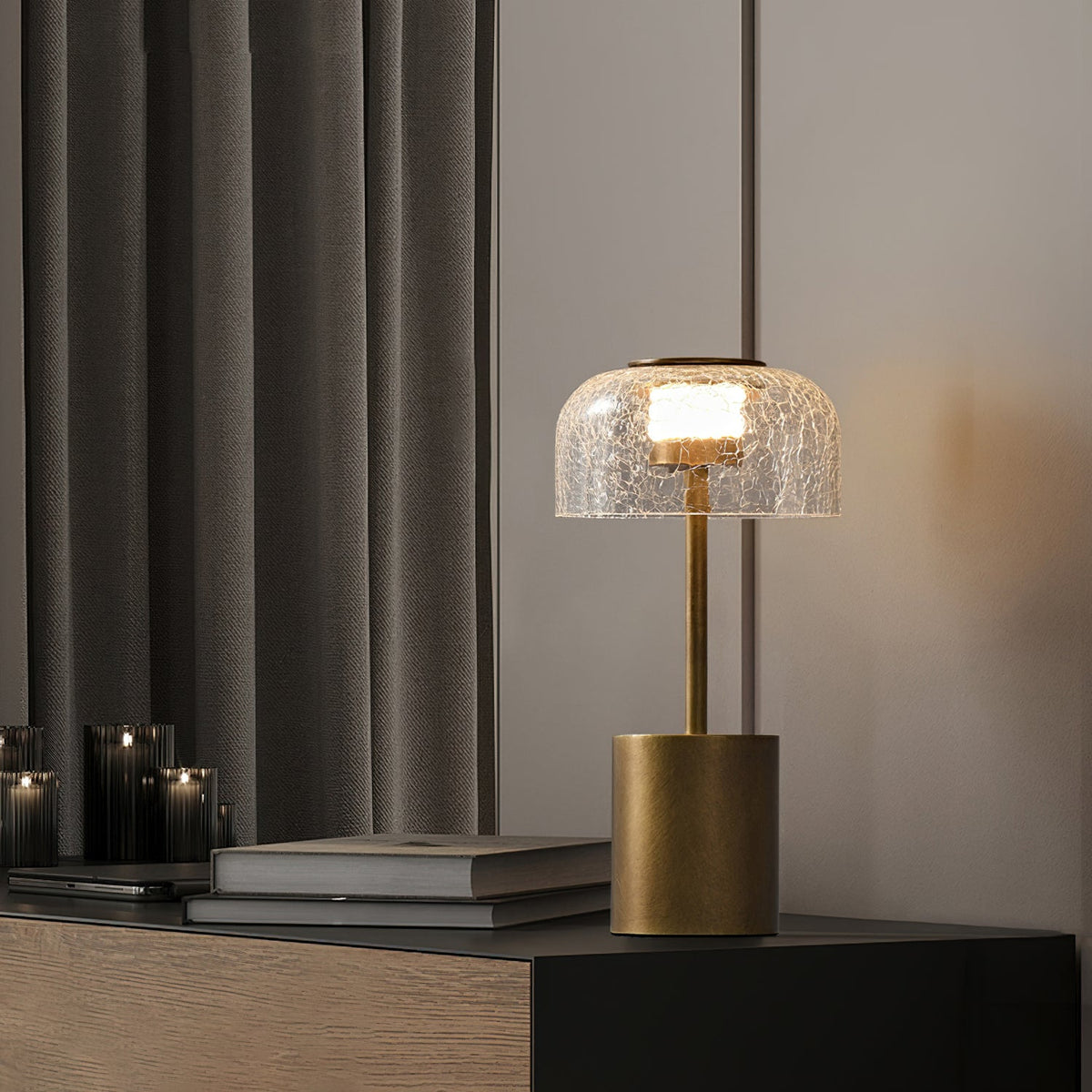 A finger touches the metal cap of this Clérachic crackle glass table lamp, which glows warm inside the dome.
