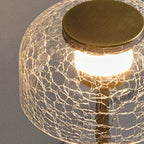 Close detail of the cracked-glass dome of this Clérachic table lamp, with its warm light and brushed bronze cap.