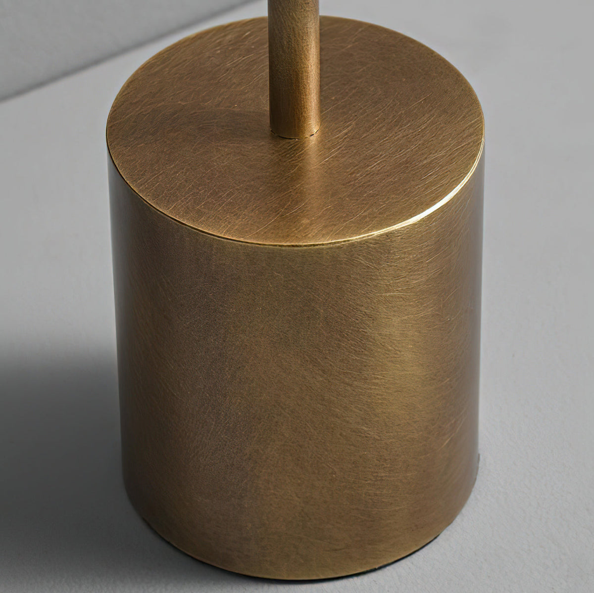 Close view of the brushed bronze base of this Clérachic table lamp, with the slim stem rising from its flat top.