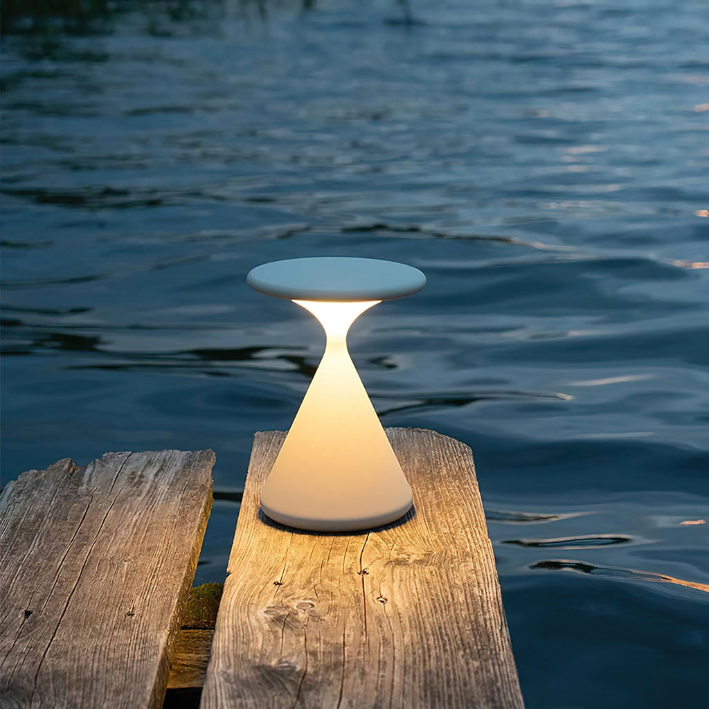 This Clérachic table lamp glows warm on the edge of a weathered wooden jetty, with dark water behind it.