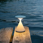 This Clérachic table lamp glows warm on the edge of a weathered wooden jetty, with dark water behind it.