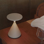 Cream Clérachic table lamp on a dark wooden table beside the edge of a white cloth and a wine glass.