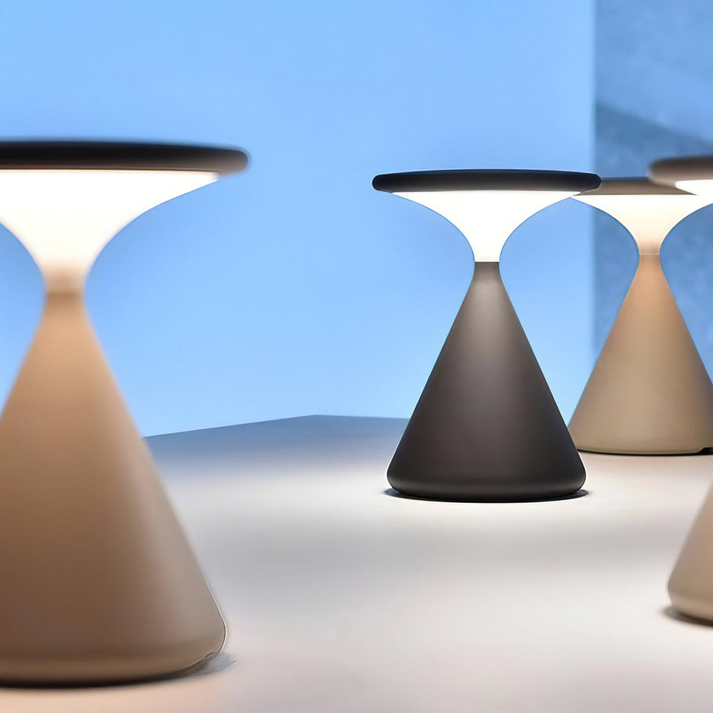 Three Clérachic table lamps in black and cream, lit against a clear blue background, seen up close.