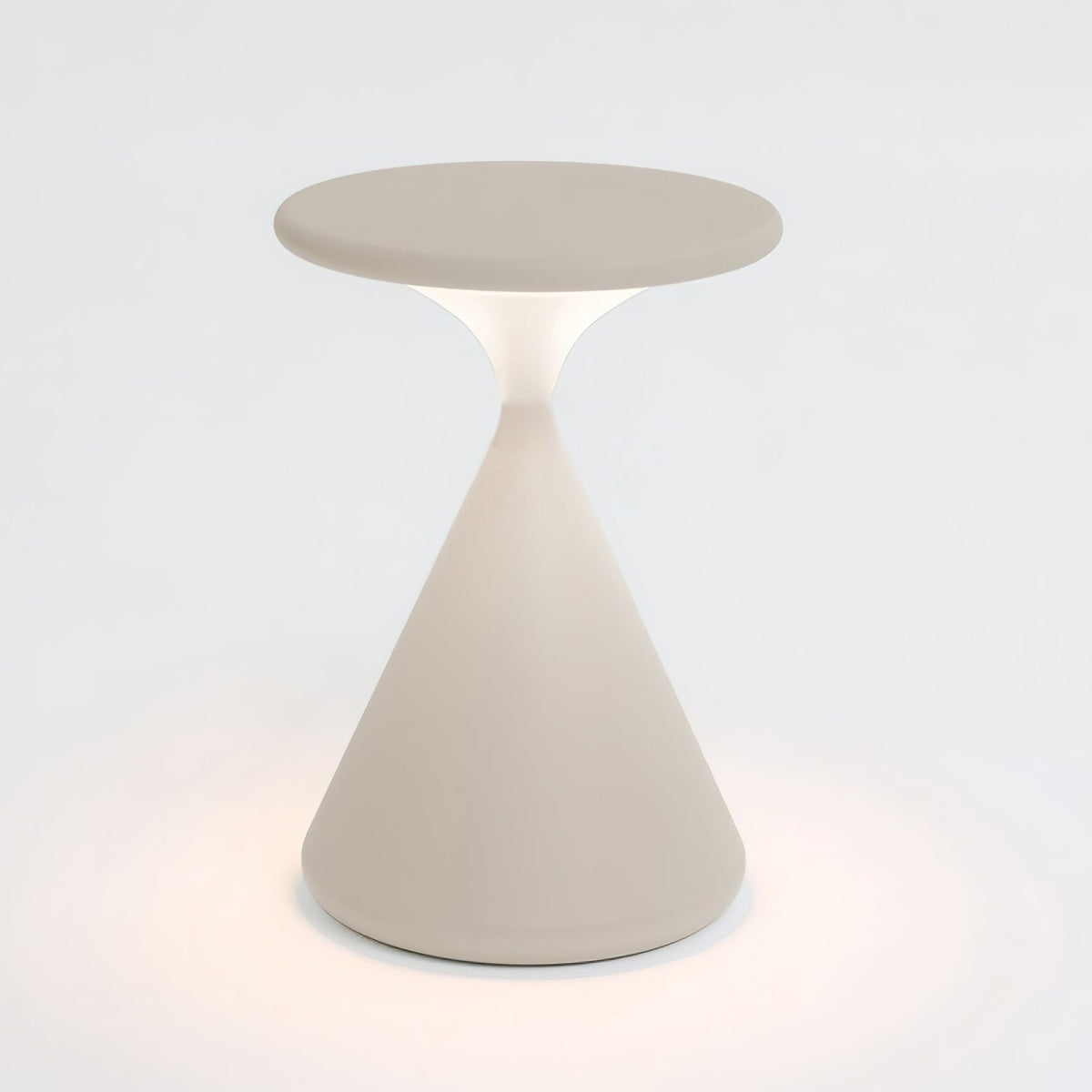 Cream Clérachic table lamp lit on a pale backdrop, with a soft warm glow around the base and under the disc top.