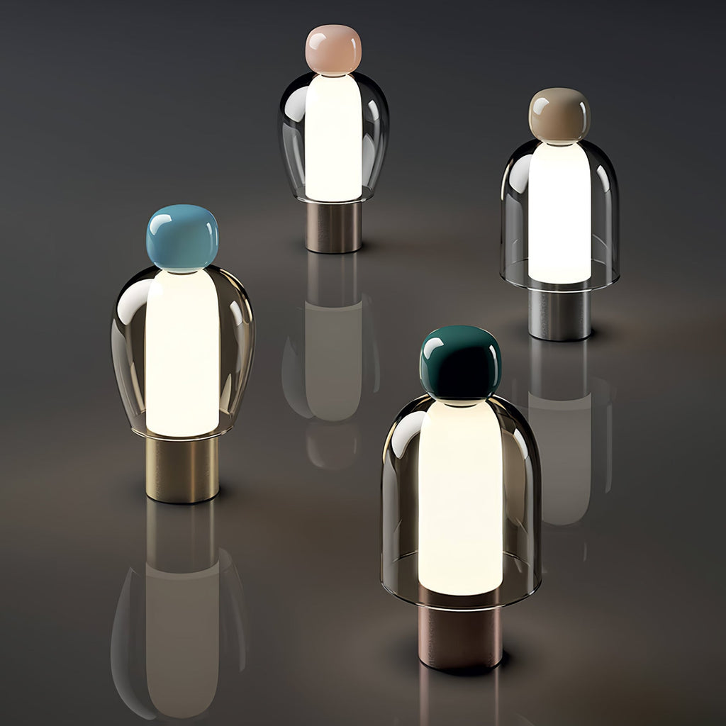 Four lit Clérachic table lamps with pink, brown, blue and dark green caps, scattered on a dark glossy floor with soft reflections.