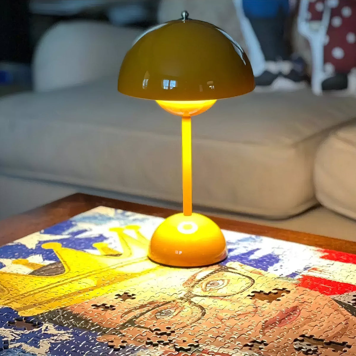 Close view of a lit yellow dome shade and stem on this Clérachic table lamp, standing on a jigsaw puzzle.