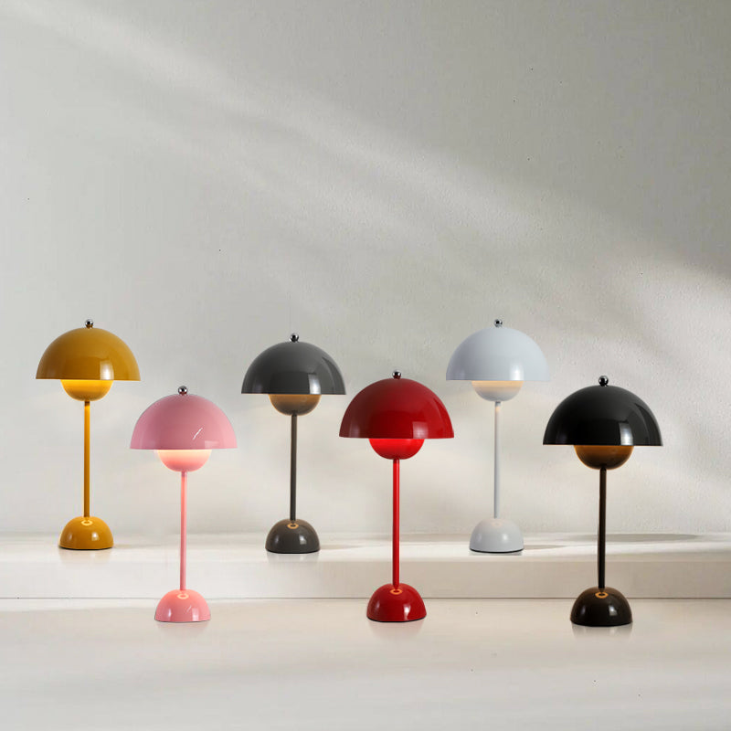 Six Clérachic table lamps in mustard, pink, grey, red, pale grey and black, standing in a row on a white ledge.