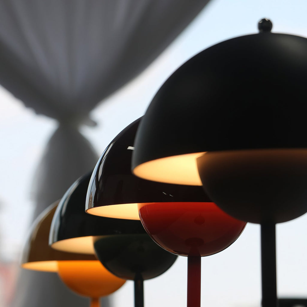 Close view of matt black and red shades on these Clérachic table lamps, with a warm light glowing under the rims.