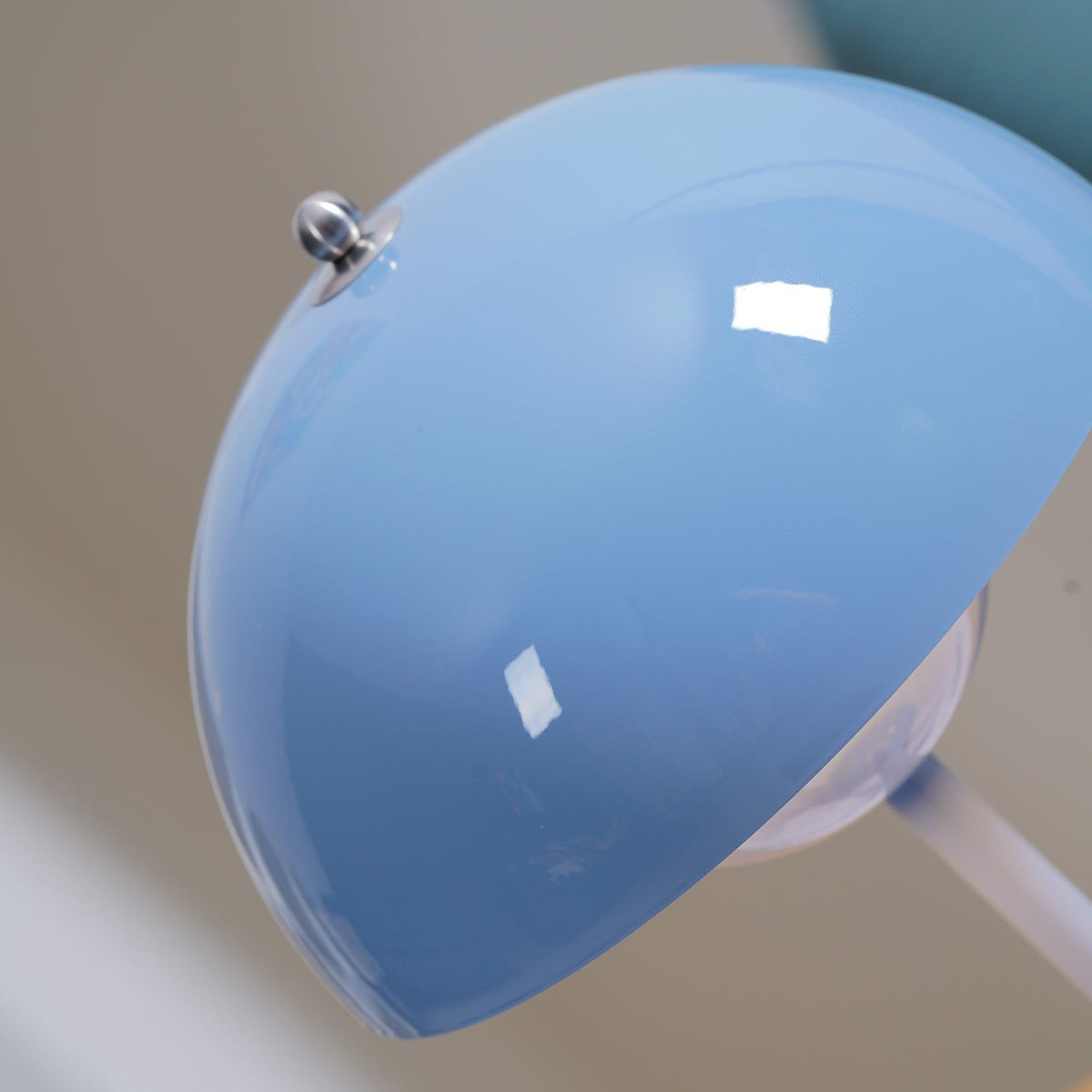 Close view of a glossy light-blue dome shade on this Clérachic table lamp, with its small metal top knob.