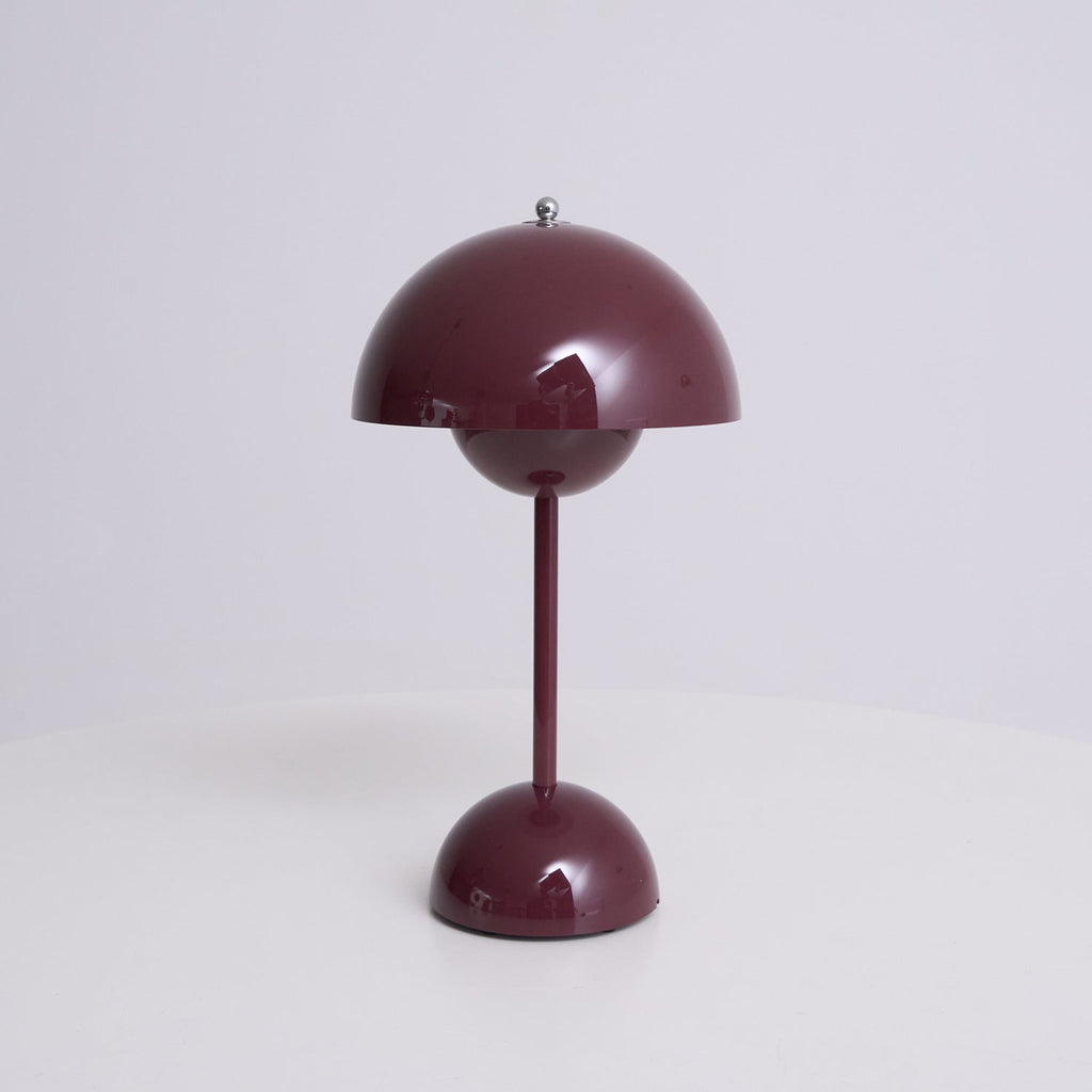 A deep plum Clérachic table lamp unlit, on a plain pale backdrop, showing its dome shade and rounded base.