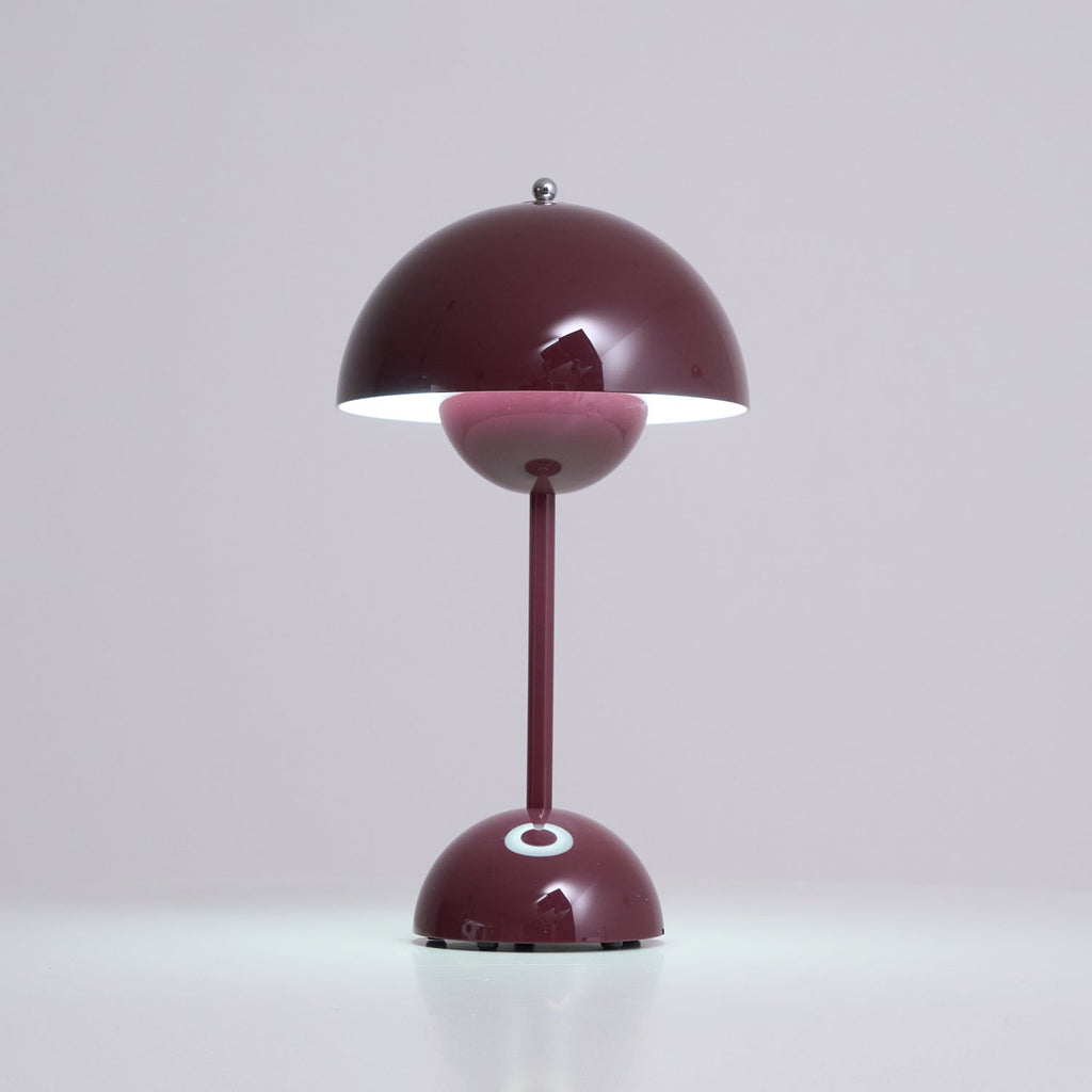 A deep plum Clérachic table lamp lit, with a white glow under the shade and a bright touch spot on the base.