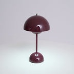 A deep plum Clérachic table lamp with a bright touch spot on its base and light pooling on the surface below.