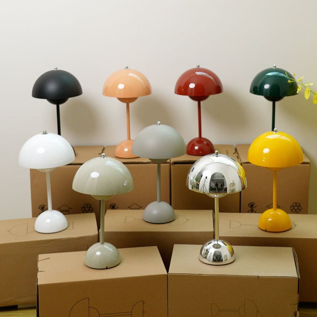 Nine Clérachic table lamps in black, peach, red, green, white, grey, sage, chrome and yellow, arranged on cardboard boxes.