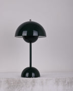 A dark-green Clérachic table lamp unlit, on a pale stone ledge against a soft grey backdrop.