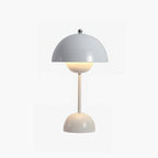 A pale grey Clérachic table lamp lit, with a slim cream stem and rounded base, on a white backdrop.