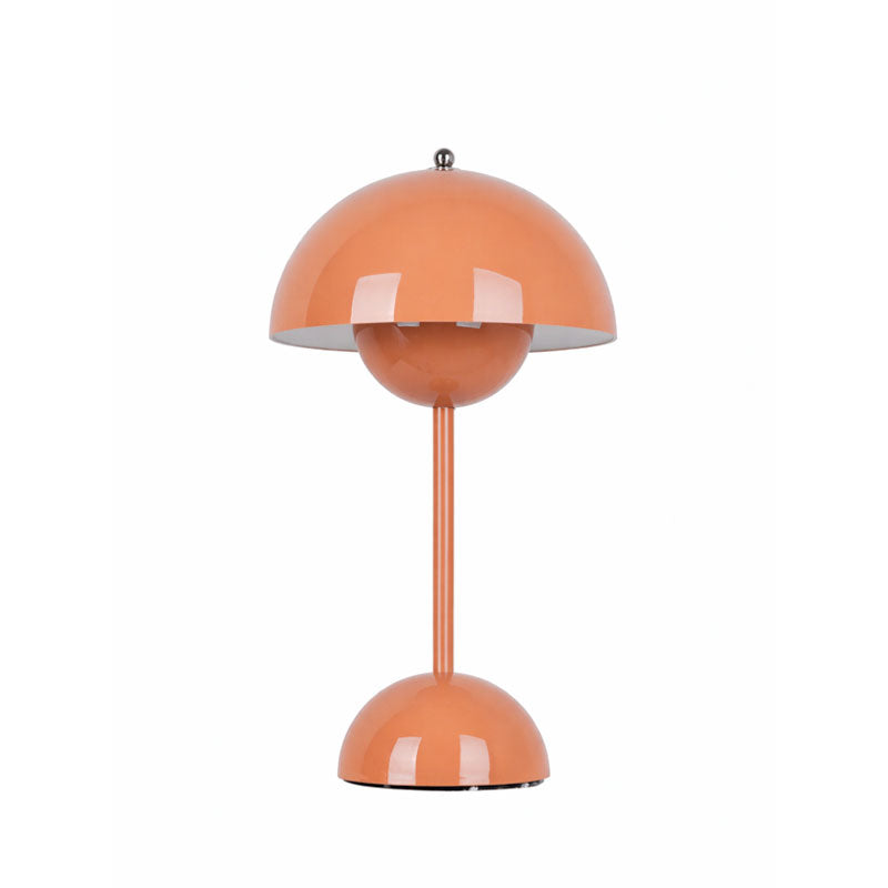 An orange Clérachic table lamp lit, with a glossy dome shade and a rounded base, on a plain white backdrop.