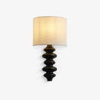 Wall light from Clérachic with a half-drum white linen shade above a black corrugated wood column, on a plain white backdrop.
