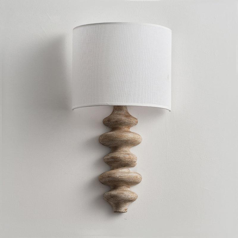 Clérachic wall light switched off, with a natural wood corrugated column and a white linen shade on a pale wall.