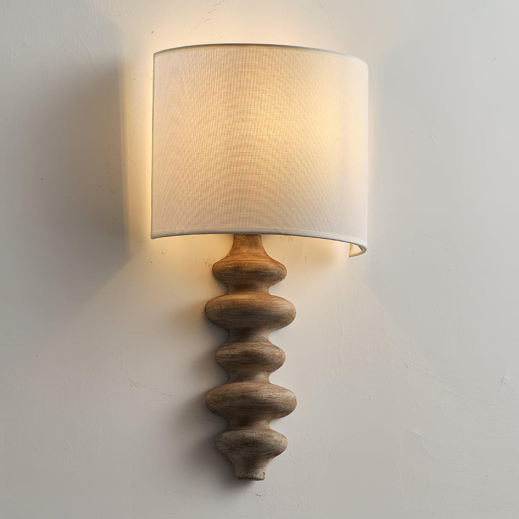 Natural wood Clérachic wall light with a white shade, softly lit, showing the grain on the stacked column below.