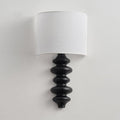 Clérachic wall light switched off, with a white linen shade over a black corrugated wooden column on a light wall.