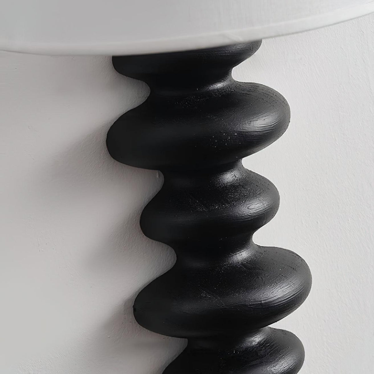 Close view of the black corrugated wood column on this Clérachic wall light, with brush marks visible on the rounded ridges.