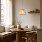 Over a round oak table in a window nook with a cushioned bench, this Clérachic pendant light hangs on a single cord.