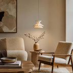 This Clérachic pendant light hangs over a corner with a bouclé chair, a stone side table and an abstract painting.