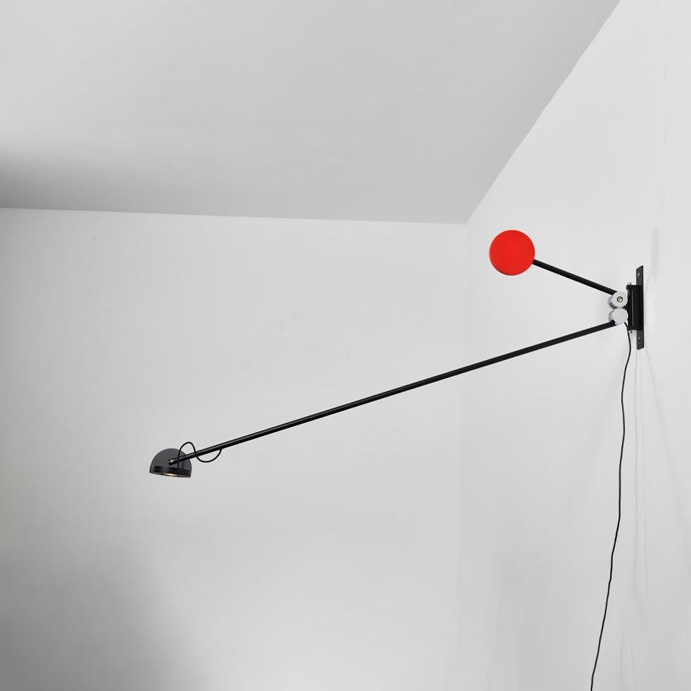 Clérachic arm light in a white corner, a long black arm stretching away from the wall with a red counterweight disc beside the mount.