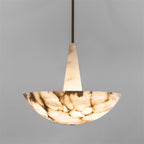 The Clérachic Cove pendant head-on: tapered alabaster stem meeting the upward-facing bowl, veining lit from inside the stone