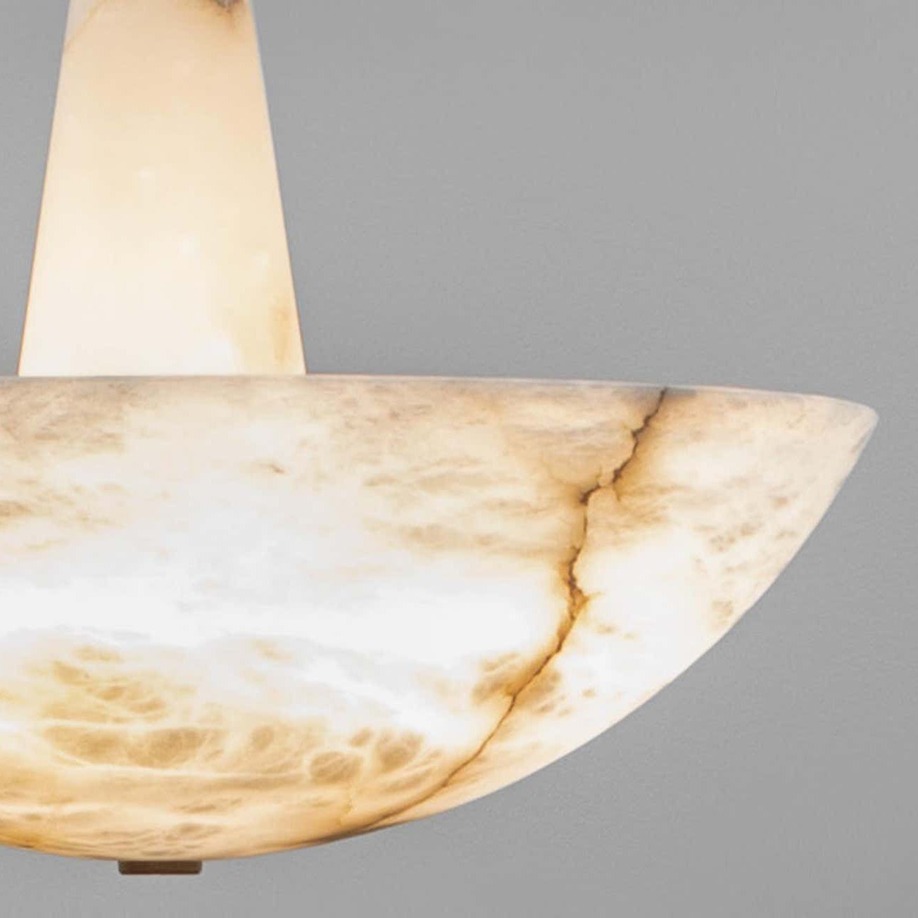 Close-up of the Clérachic Cove pendant's alabaster bowl rim and tapered stem, a fine dark vein running through cream stone