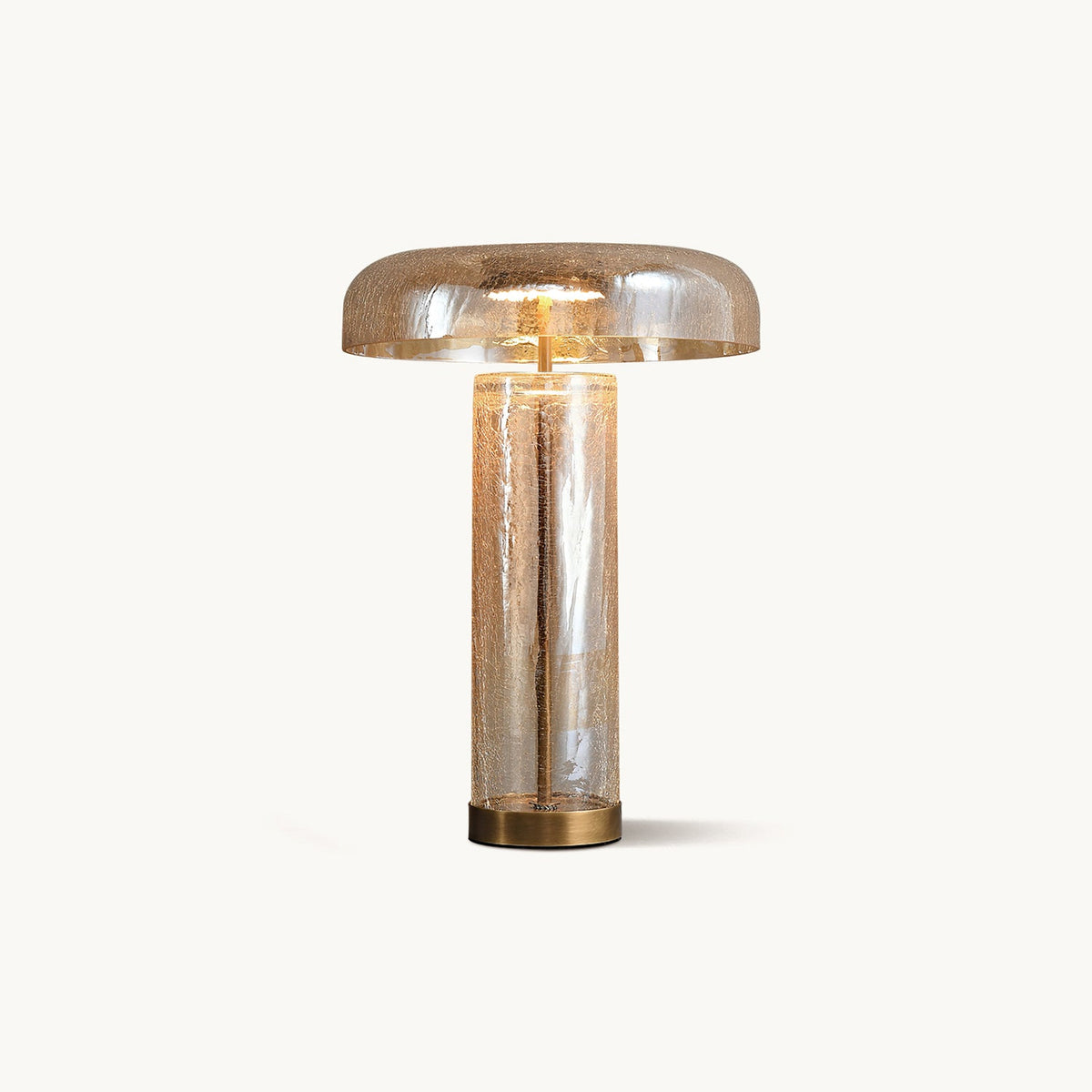 Crackle glass table lamp from Clérachic with an amber domed shade, a clear cylinder body and a bronze base, on white.