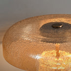 Close view of the amber crackle-glass dome on this Clérachic table lamp, with a small bronze cap on top and light inside.