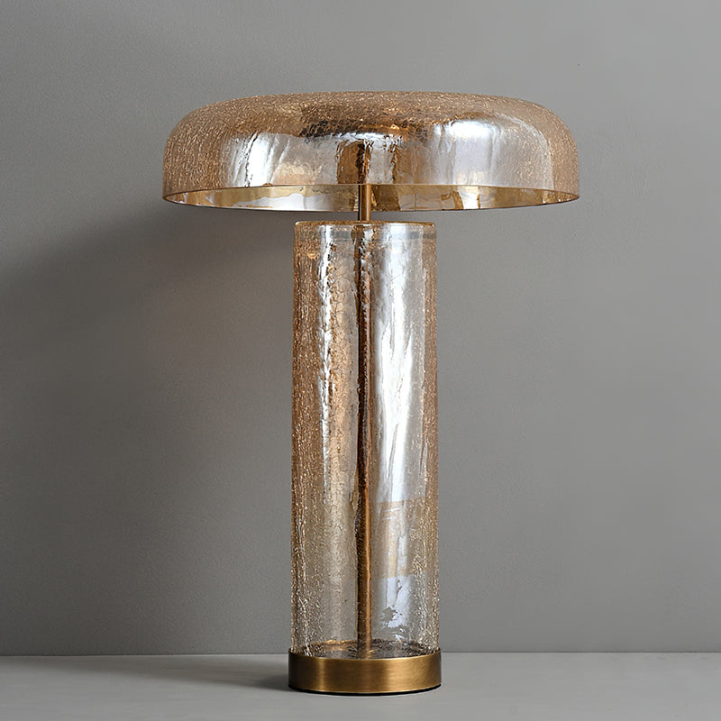 Clérachic crackle-glass table lamp switched off on a grey ledge, its amber dome and clear cylinder showing a fine crack pattern.