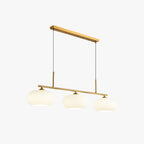 Three-quarter view of the Clérachic cream glass pendant light in gold, three glowing shades on a slim gold bar.
