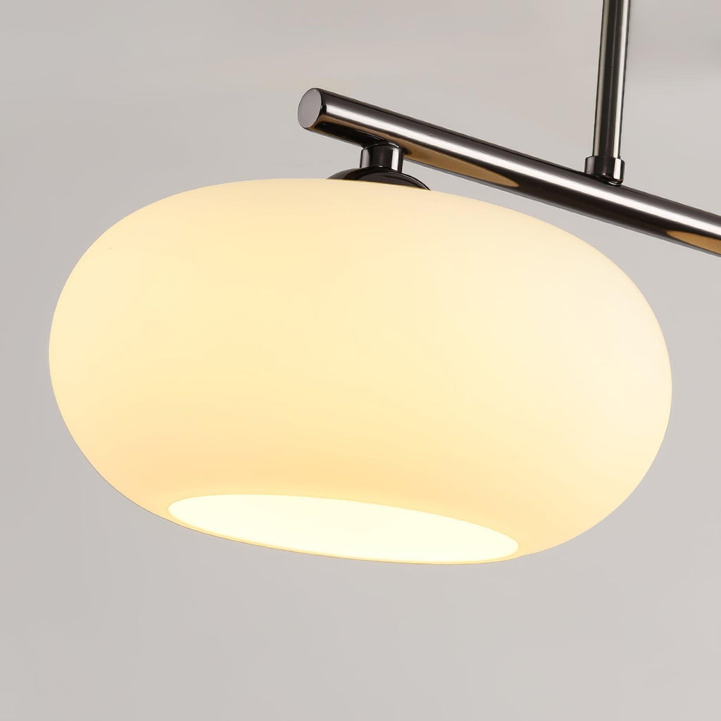 Close-up of one Clérachic cream glass shade on the silver-frame cluster, warm light spilling from the open base.