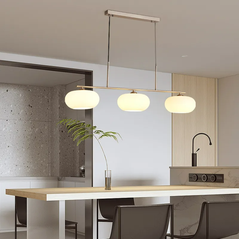Clérachic gold-frame cream glass cluster over a wood island, cream shades lit against a speckled stone kitchen wall.