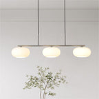 Clérachic cream glass 3-light cluster on a silver bar, three lit pebble shades above a leafy green branch.