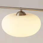 Close-up of a Clérachic cream glass shade on the gold-frame cluster, gold dome cap seated on the glowing globe.