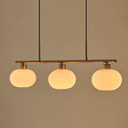 Clérachic cream glass 3-light cluster in gold, three lit oval shades on a gold bar against a warm beige ground.