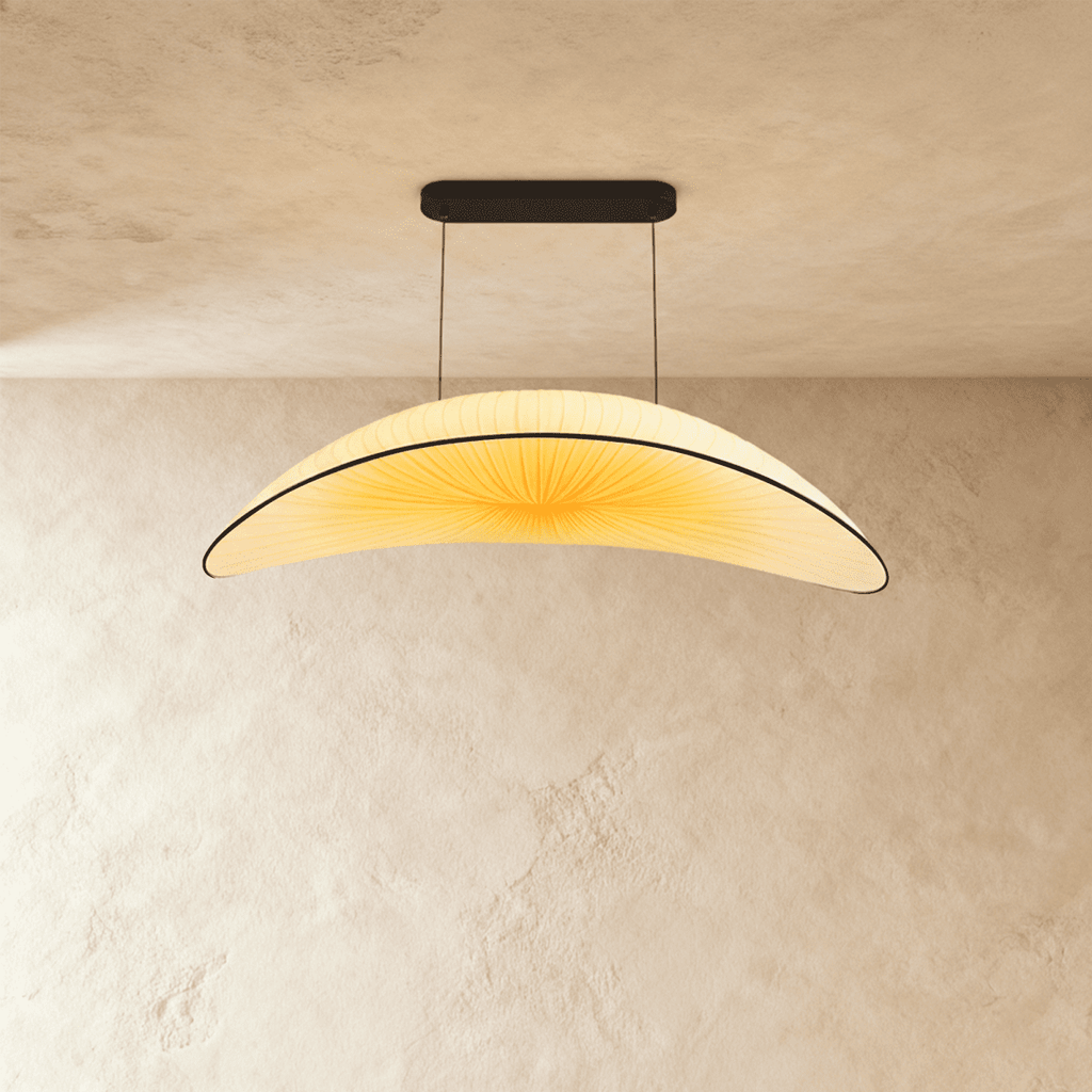 Clérachic cream pleated-fabric chandelier in a curved leaf shape, its shade glowing warm white below a black ceiling canopy.