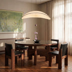 The Clérachic cream fabric chandelier glowing warm white above a round walnut dining table set with a single orchid stem.