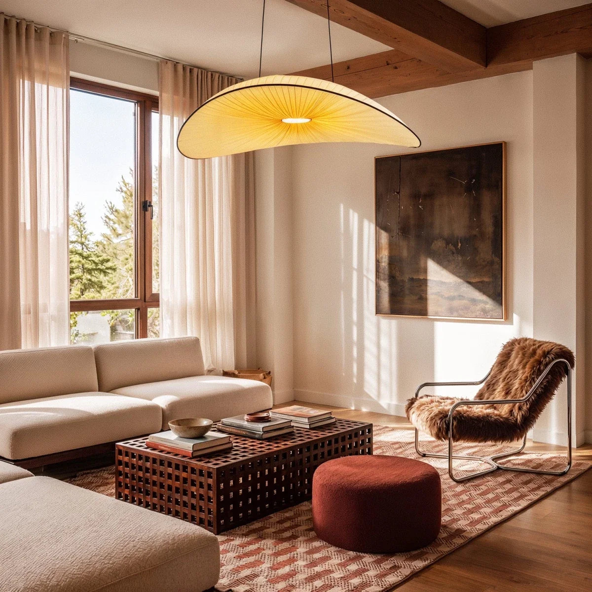 The Clérachic cream fabric chandelier glowing warm white above a living room with a cream sofa and a rust bouclé pouf.